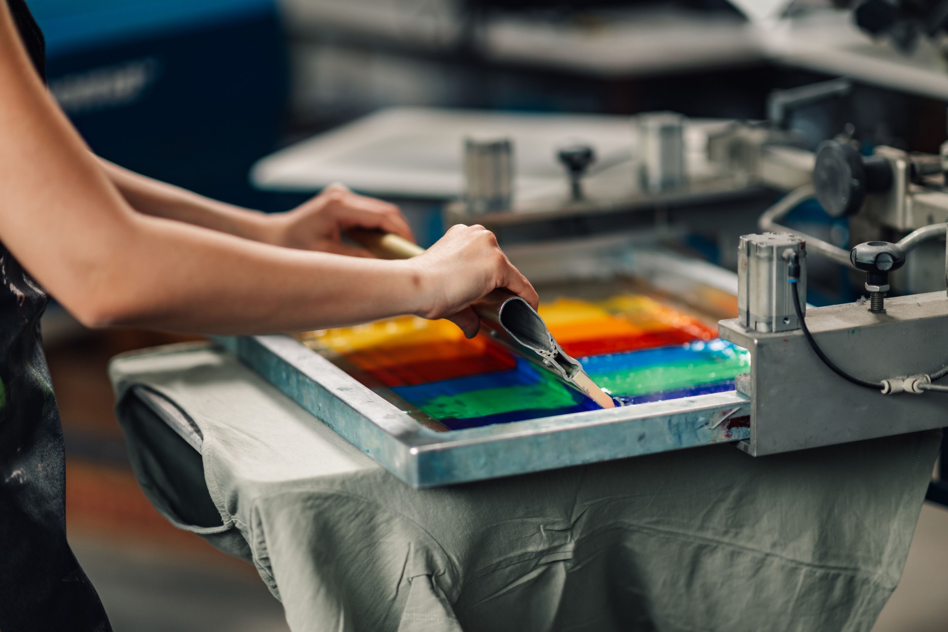 Close up of unrecognizable worker's hands screen printing with squeegee