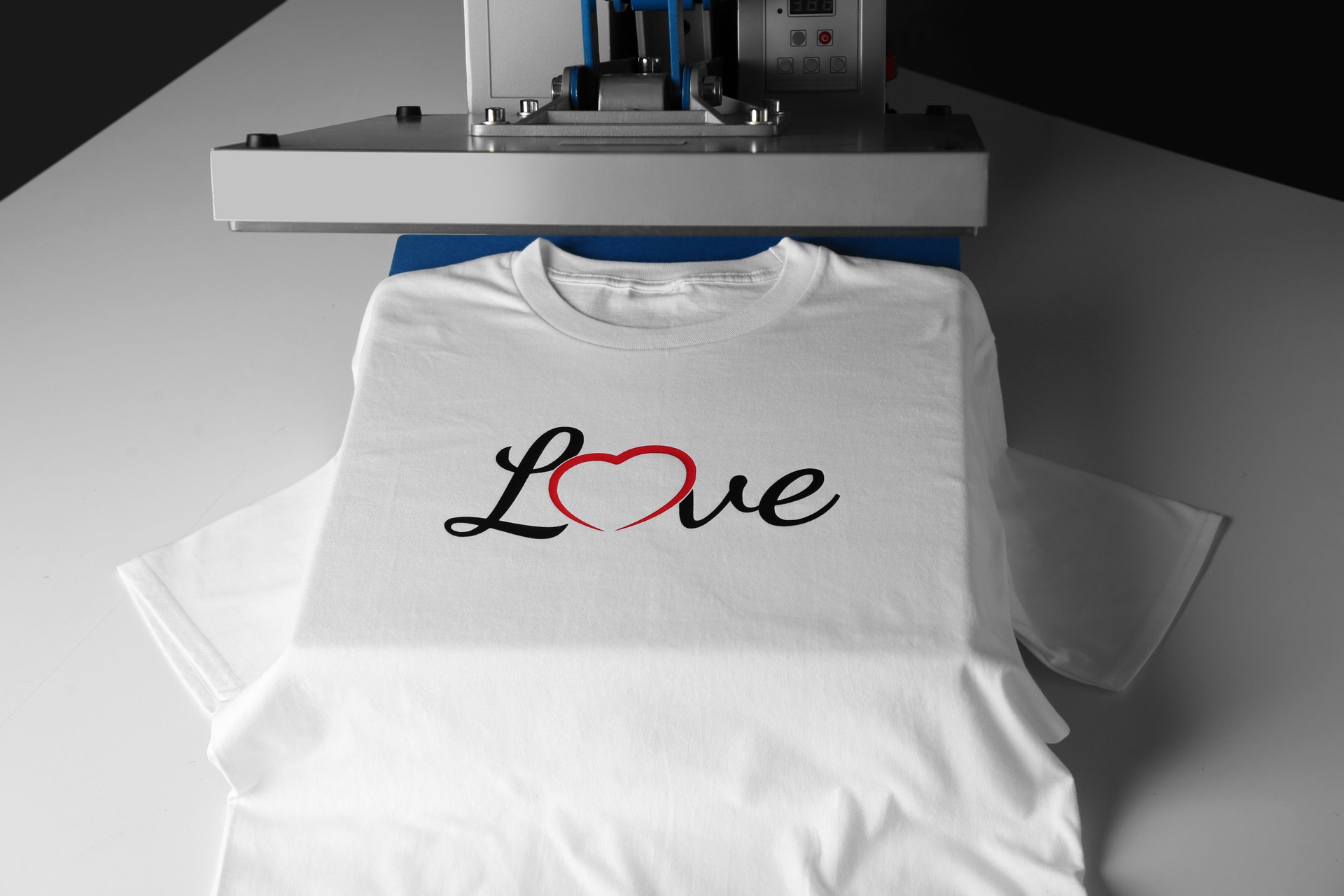 Printing logo. Heat press with t-shirt on white table