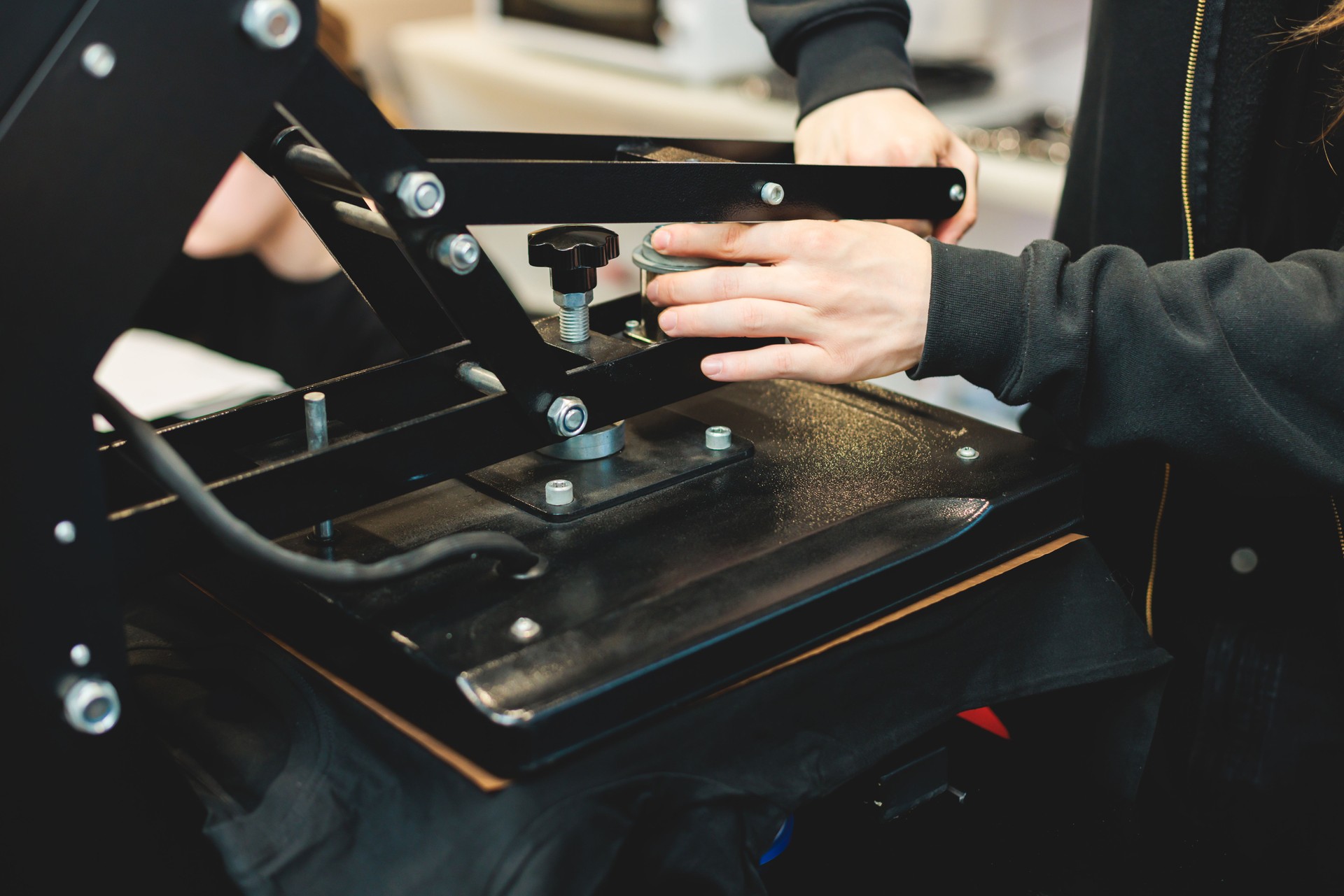 Process of printing image on clothes, heat press machine printing custom design on t-shirt and hoodie in fabric workshop, screen printing shirt, textiles and clothing, lithography and serigraphy